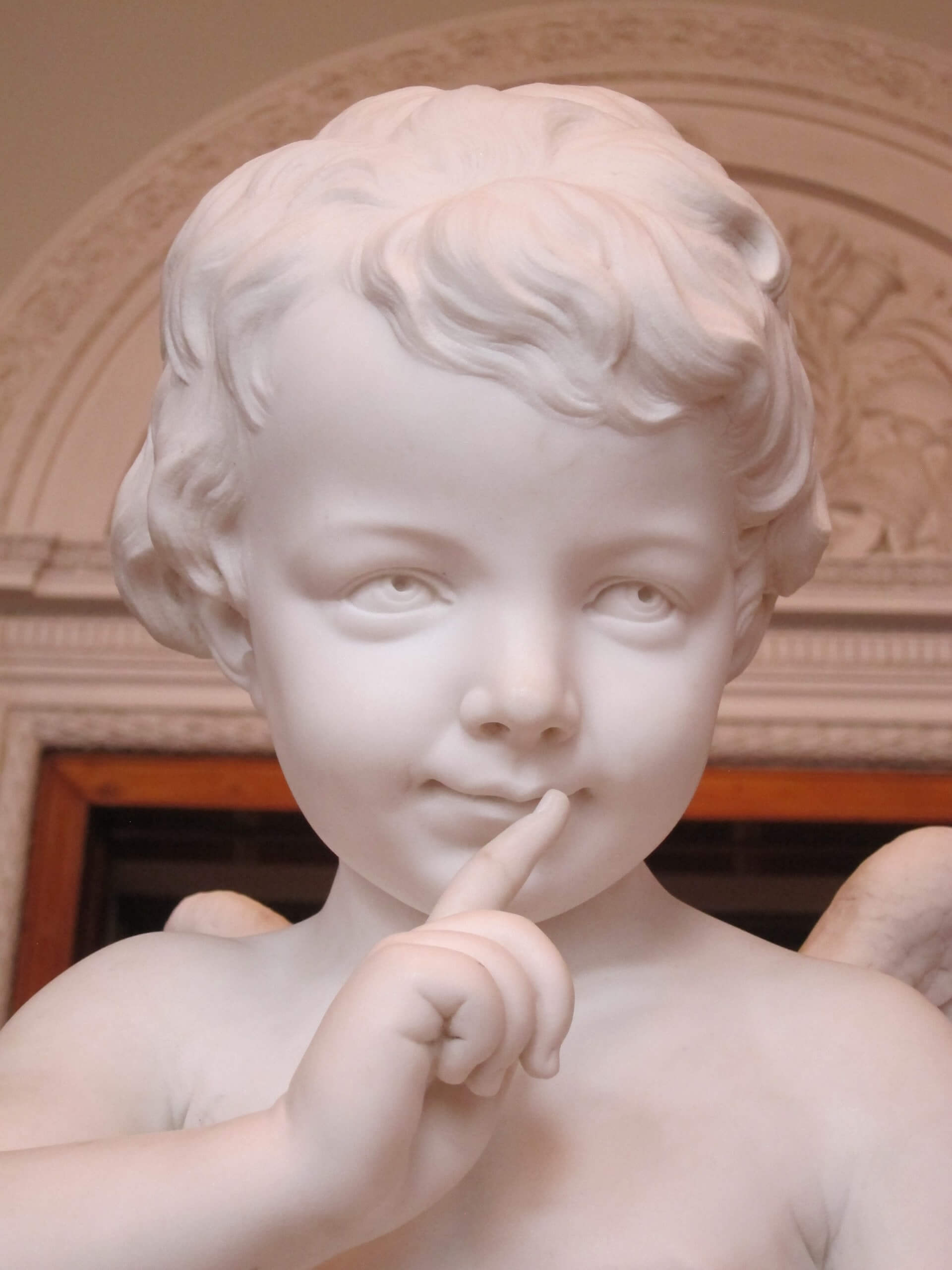White statue of a mischievous looking boy